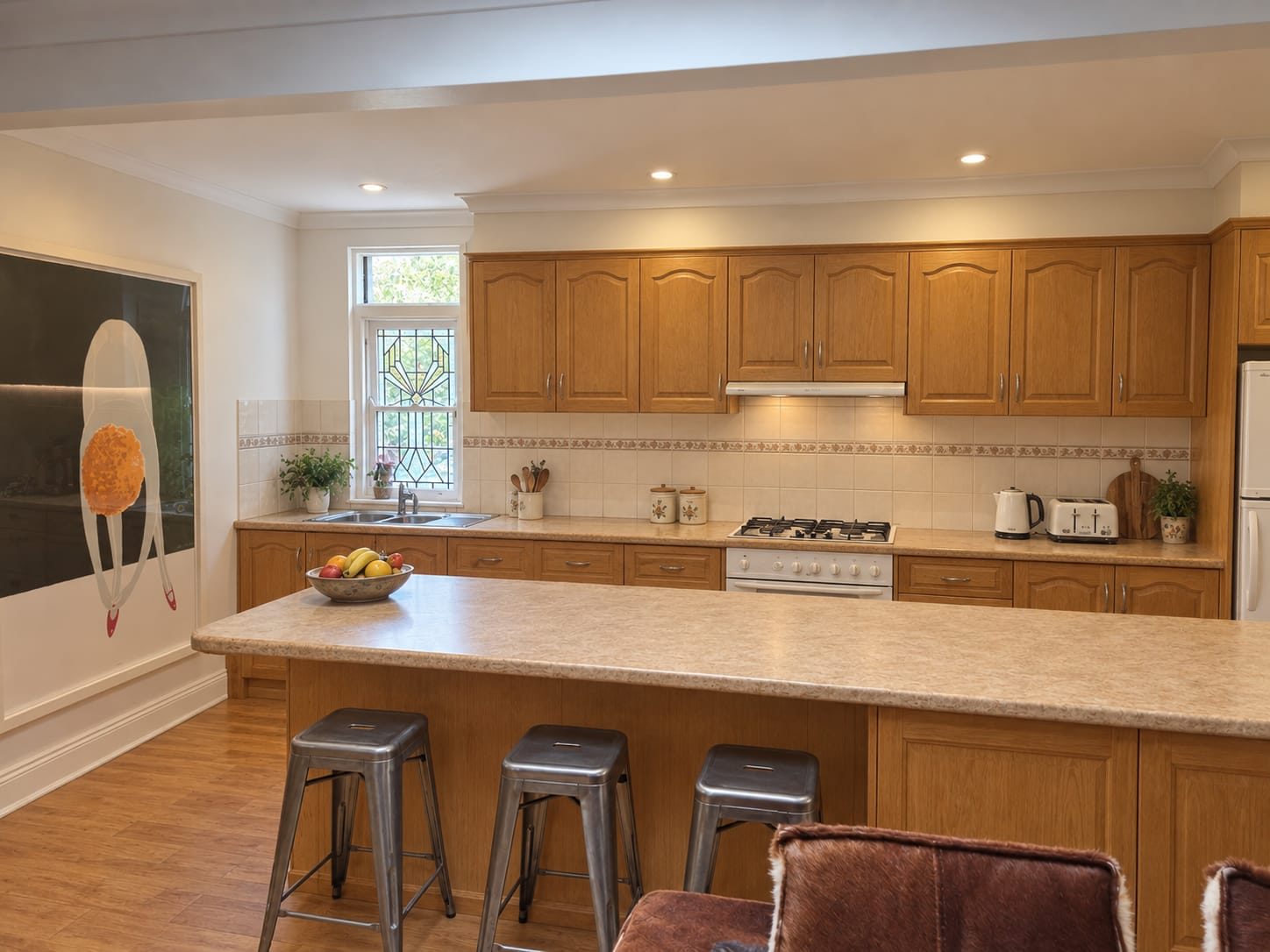 The original kitchen before renovation, with honey oak cabinets, arched door fronts, speckled laminate benchtops and a tiled splashback